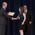 Doctor Potteiger shaking hands with an award recipient in a teal and black shirt